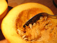 a fresh pumpkin being scooped out with a spoon